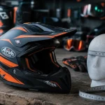 Casque moto cross Airoh noir et orange sur établi